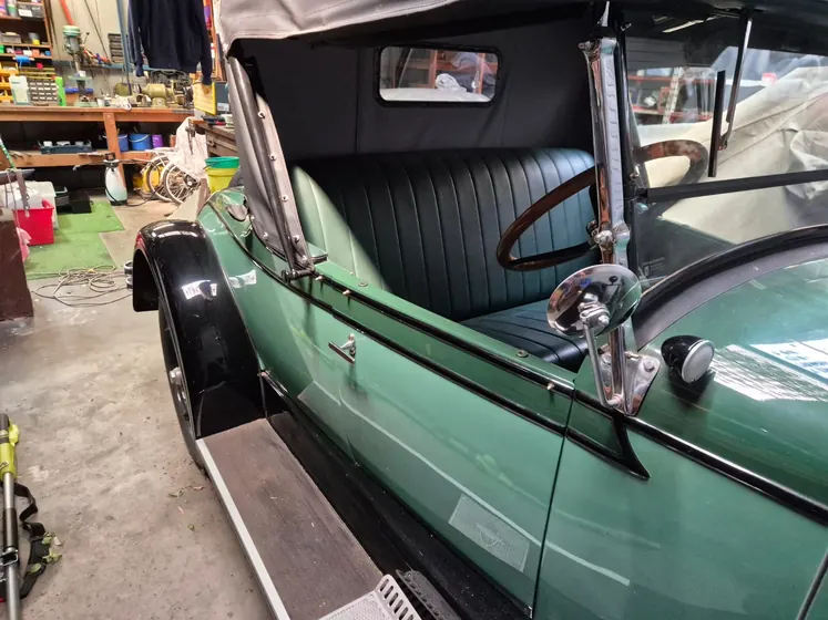 c1928 Chevrolet Roadster with the hood raised, showing the green bodywork, black leather seat, windscreen and running board