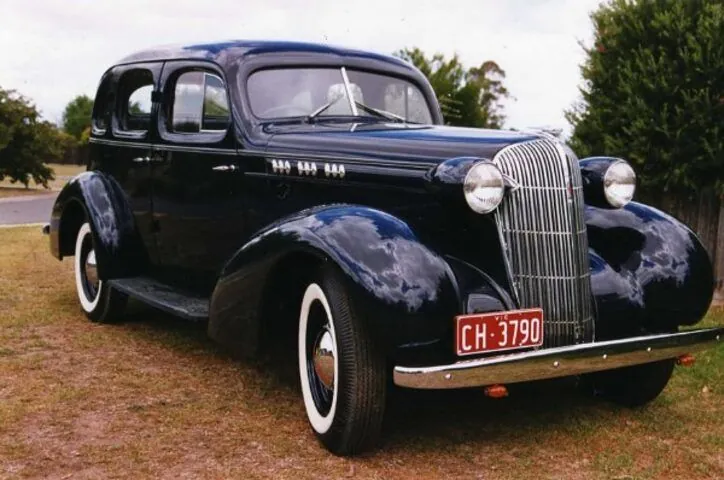 c1936 Oldsmobile F-37 four-door sedan in dark blue, front three-quarter view with whitewall tyres