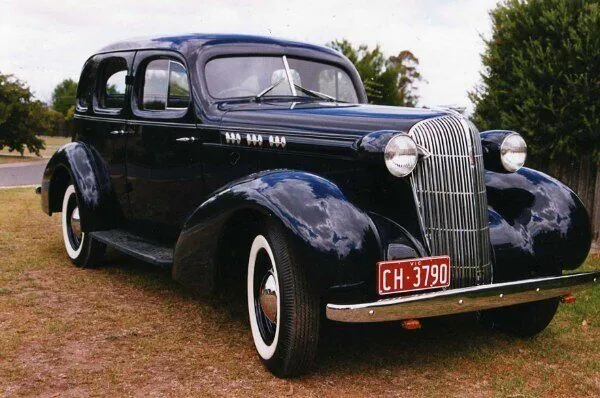 c1936 Oldsmobile F-37 four-door sedan in dark blue, front three-quarter view with whitewall tyres