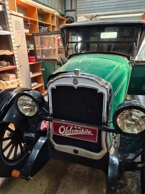 Close view of the enamel 1925 Oldsmobile radiator badge and headlamps on the Model 30 Tourer