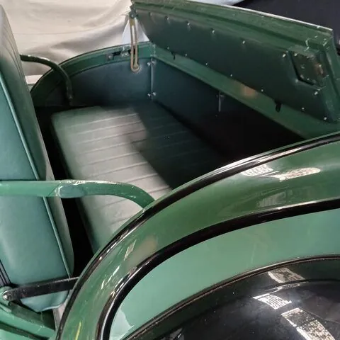 Dicky seat of the c1928 Chevrolet Roadster open, showing the upholstered seat and the hinged lid in green
