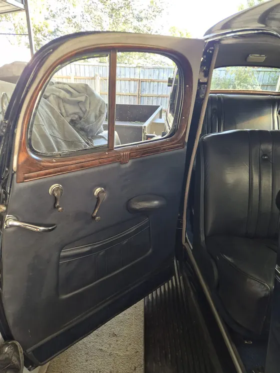 Front door open on the 1936 Oldsmobile F-37 sedan showing the woodgrain window garnish, door card and leather front seat