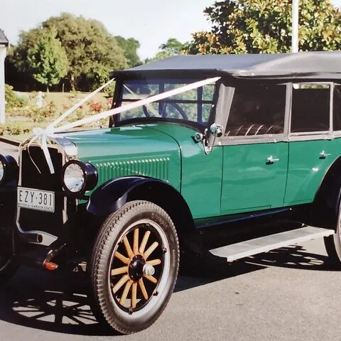 Front three-quarter view of the c1925 Oldsmobile Model 30 Tourer dressed with white ribbons for a wedding