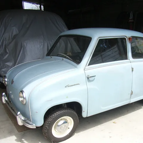 Front three-quarter view of the original unrestored c1958 Goggomobil T300 sedan in light blue, parked in a shed