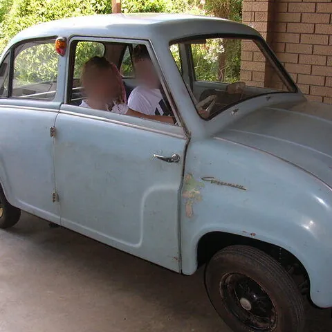 Original unrestored c1958 Goggomobil T300 sedan in light blue, full side view under a carport