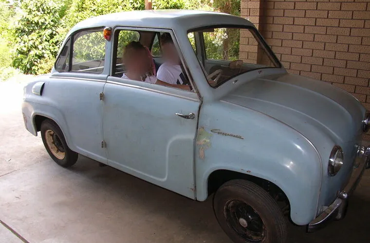 Original unrestored c1958 Goggomobil T300 sedan in light blue, full side view under a carport