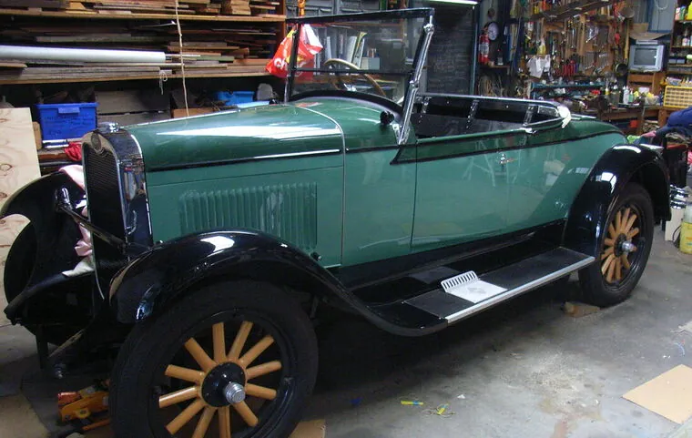Restored c1928 Chevrolet Roadster in green with black guards and timber-spoke wheels, hood down, side three-quarter view